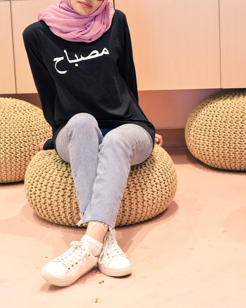 Black tshirt with name printed in arabic in white worn with head scarf and jeans